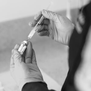 A healthcare worker prepares a syringe with medication in a clinical setting.