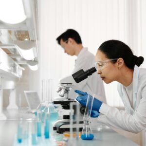 Two scientists in a lab examining samples with a microscope. Focus on scientific research and discovery.