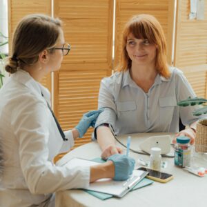 Doctor measuring patient's blood pressure with digital monitor in a clinical setting.