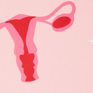 Abstract representation of sperms approaching an ovum, symbolizing fertilization on a pink background.