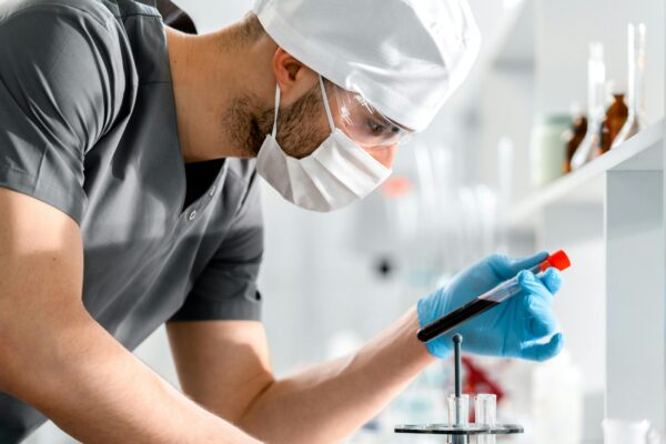 A researcher in a lab coat carefully examines a test tube, symbolizing scientific discovery and research.