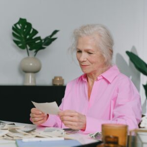 Elderly woman enjoying memories through old photographs, indoors setting.