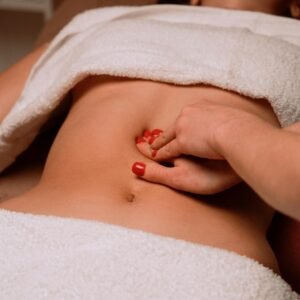 A soothing massage on a woman's abdomen with painted nails, creating a serene spa atmosphere.